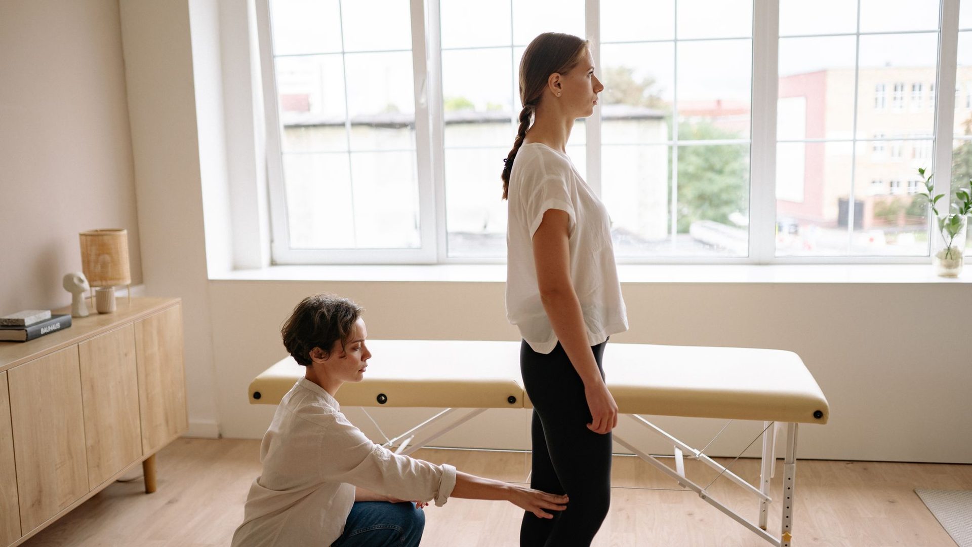 Heller Behandlungsraum einer Physiotherapiepraxis mit Therapeutin und Patientin während einer Bewegungstherapie