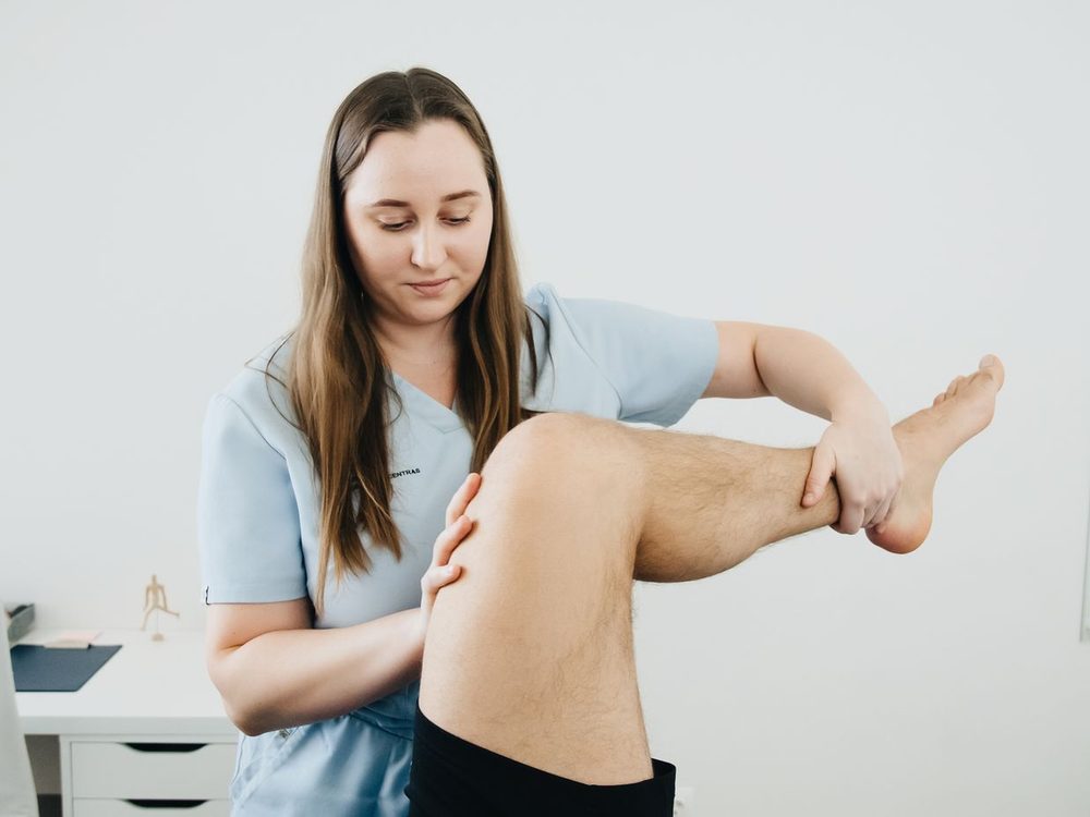 Physiotherapeutin mobilisiert das Bein einer Patientin während einer krankengymnastischen Behandlung