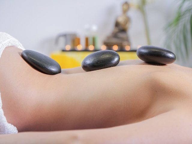 Warme Steine liegen bei einer Hot-Stone-Massage auf dem Rücken einer Frau